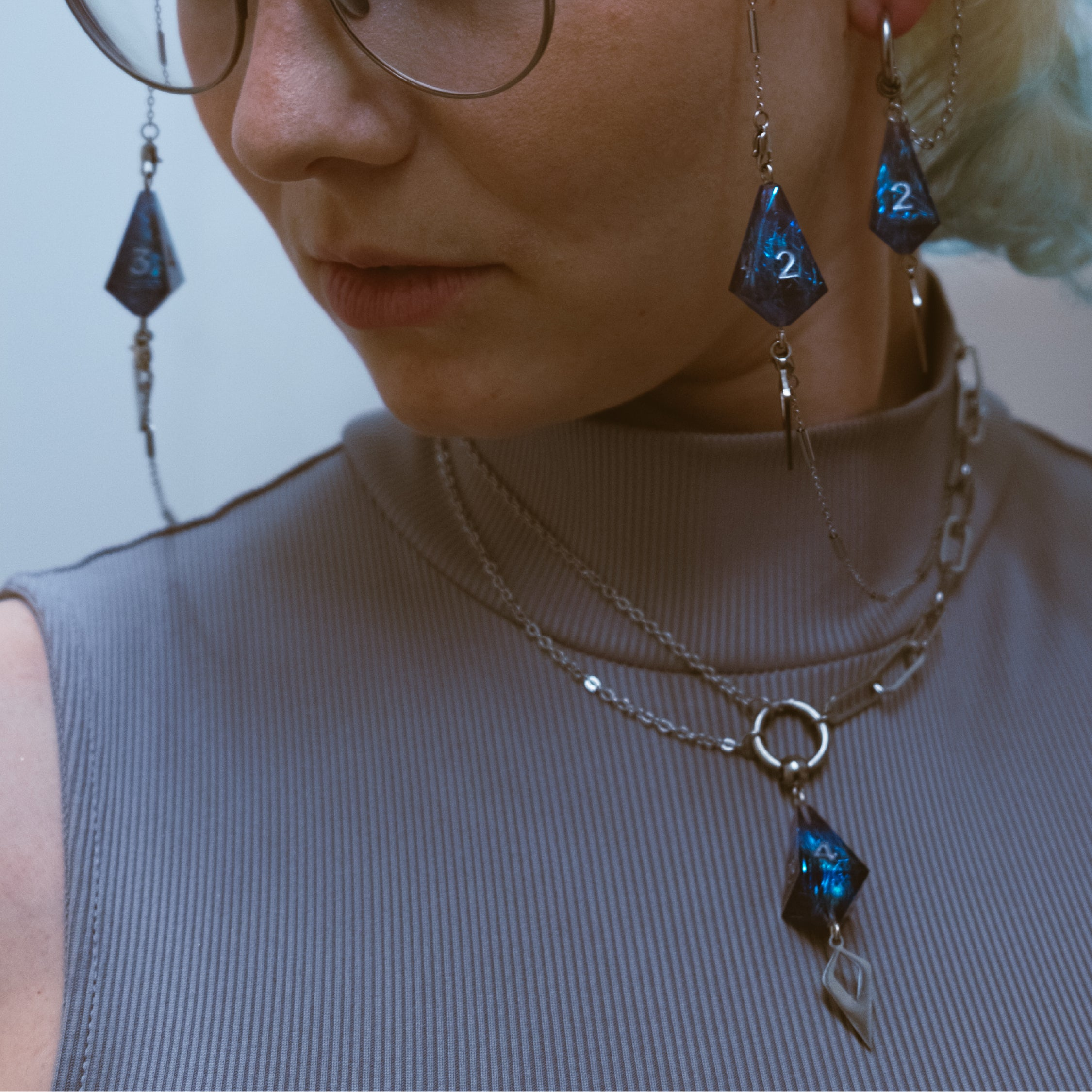 Close-up of a person wearing blue gemstone earrings and necklaces.